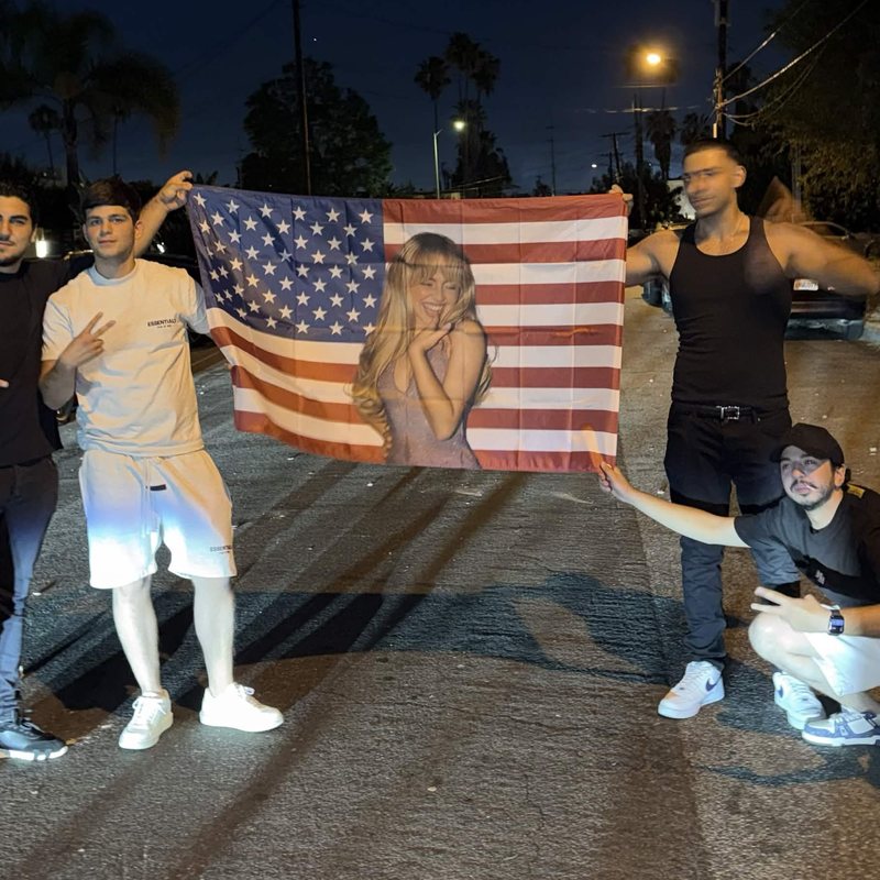 Friends holding a face-on-the-flag custom flag on the street at night